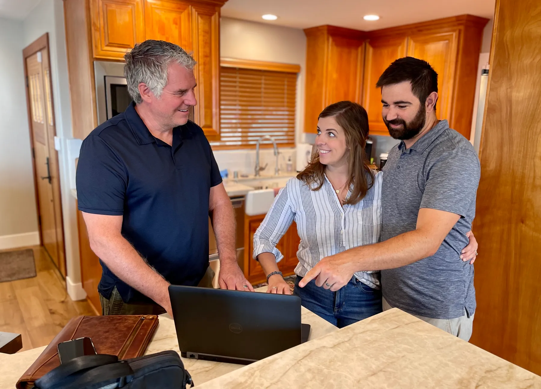 Bob Clardy reviewing an inspection report with clients at a kitchen counter